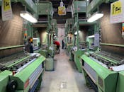 Industrial production line in Narayanganj, Bangladesh with workers at textile machines.